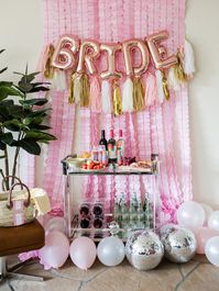 Wedding Wednesday: 5 Essentials You Need For The Perfect Bachelorette Party · Haute Off The Rack, Bachelorette Set Up, How to Decorate for your bachelorette party, Bride Balloons, Tassel Garland, Disco Balls, Bar Cart, Streamers, Barrington Beach Bag