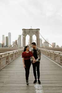 Couple walking in Dumbo Brooklyn with the Brooklyn Bridge in the background. New York City engagement session. Brooklyn Dumbo engagement session, Brooklyn wedding photographer, NYC wedding photographer. Anais Possamai Photography