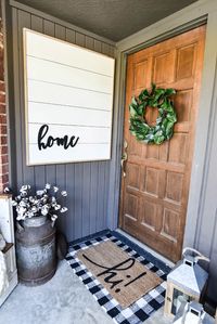 How to Create a Neutral Fall Front Porch Style - Our Handcrafted Life How to decorate a neutral front porch with a simple, farmhouse style for Fall. We used pumpkins, lanterns, rugs, and DIY projects to create the perfect front porch design for autumn. We included patterns and textures like a buffalo check rug doormat, cotton stems in an antique milk jug, a faux shiplap sign, a magnolia wreath, a chunky knit blanket, a faux church pew, and white pumpkins.