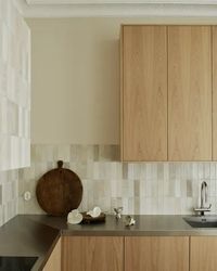 Natural oak kitchen cabinets combined with a tile backsplash and a stainless steel countertop