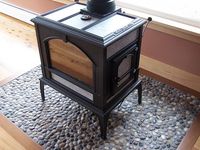 Here is the little woodstove, sitting on the pebbled surface, perfect for the beach cabin