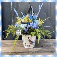 Blue /yellow Spring centerpiece was made with hydrangeas, blueberries, butterfly, mums, daisies, cosmos, and greenery. This artificial flower arrangement was made in a cream colored tin with a nature motif. Perfect for your home, office, a gift, and for Mother's Day!