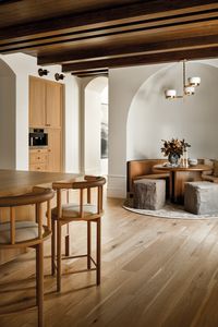 To create an elegant architectural moment, Galloway designed a leather-covered banquette and white oak table that fit seamlessly within an arched breakfast nook’s inviting curve. The ottomans are from the designer’s eponymous shop. She also customized the nearby island’s counter stools.