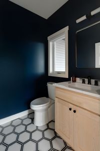 Hexagon tiles, dark blue paint, light wood vanity. Modern with a twist!