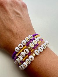 5 Piece Bracelet Stack - LSU Tigers Time to show off your school spirit with this handmade 5 piece bracelet stack! Handmade from durable elastic rubber cord, glass seed beads and acrylic letter beads, these bracelets are sure to make a statement and spread cheer. Included: Two purple and gold patterned glass bead bracelets One "Geaux Tigers" phrase bracelet One "I <3 LSU" phrase bracelet One "Purple * Gold" phrase bracelet Sealed in packaging suitable for gift-giving! Available in three size options.  7 inches is standard/adult and fits most all adult wrists.  6 inches is suitable for small adult wrists and kids 8 and up.  5.5 inches is child's sized and will fit most kids 4-8 years old.  *Please message me if you require a size other than the three listed and I will gladly accommodate. Pl