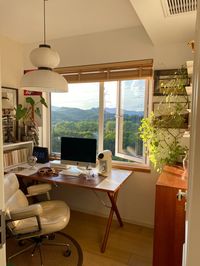 Boost your productivity and morale with a home office that offers stunning mountain views. This image features a sleek and organized workspace with a computer setup positioned in front of a large window overlooking mountains.