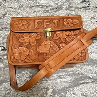 Beautiful handcrafted hand tooled saddle leather bag with interior divider The majority of the bag has what looks like hibiscus flowers as well as a cocker spaniel and letters FPT Looks new with the exception of some strap wear, see pictures