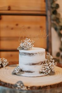 White cake with wook grain look, baby’s breath, and eucalyptus.