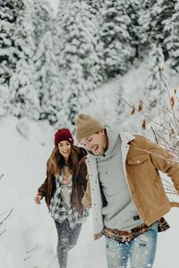 Adventurous snowy engagement pictures in the mountains. Pine trees dusted with snow. Couple laughing holding hands running. Utah wedding photographer. Couple photographer. Beanies. #utahengagementphotographer #utahcouple #utahweddingphotographer #weddingphotographer #engagementphotographer #engagements #winterengagements #winterphotoshoot