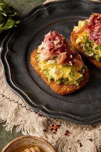 Introducing my Hashbrown Avocado Toast with Prosciutto—a delicious and satisfying breakfast or brunch option. This dish combines crispy hashbrowns, creamy avocado, prosciutto, arugula, and crumbled feta, all perfectly complemented by a drizzle of honey