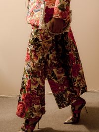 A pieced and patched tailored frock coat and kickback bumster trousers are embroidered with English florals and birds.