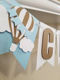 Add a special touch to your baby shower or birthday celebration with this Up Up and Away/Hot Air Balloon banner. Made to order. ALL LETTERS IN CAPSAND IN KRAFT COLOR Made for girls and boys. Select your accent color,pink, light blue, navy blue, yellow or lavender. White pennants and kraft color is also incorporated. 2 Beautiful Hot Air Ballon with clouds and mini flags ends included in each banner. Pennants measure 5 inches in height. Can be made bigger for additional charge. Letters and hot air