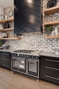 Modern Industrial kitchen design with brick backsplash and matte black appliances.