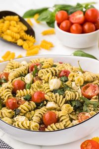 a bowl of Pesto Pasta Salad garnished with basil leaves.