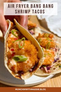 These Air Fryer Bang Bang Shrimp Tacos take inspiration from the iconic Bonefish Grill menu item, and transform it into a healthier full meal! The shrimp is air fried until perfectly crispy, then tossed in a creamy and spicy sauce, and served with homemade slaw and flour tortillas. A fun dinner recipe that’s ready in under 30 minutes!