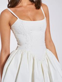 Introducing the alluring Kadi White Cotton Corset Mini Dress, a delightful addition to your wardrobe. Crafted from crisp low stretch Cotton Poplin, this mini dress exudes casual elegance. Delicate lace detailing adorns the garment, adding a touch of charm. The V-shaped waistline and the built-in bones accentuates your