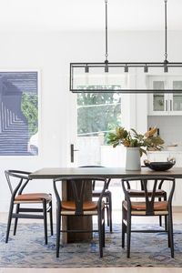 Modern, light, airy dining room connection to kitchen with wishbone chairs, wood table, modern art, and vintage rug | Studio McGee Design Blog