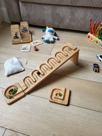 Explore the wonders of engineering and fun with our marble run track set. Crafted from high-quality wood, this maze board offers endless entertainment for kids. Watch in amazement as marbles cascade down the winding tracks, racing through twists, turns, and loops. Perfect for developing fine motor skills and fostering creativity, it's an ideal gift for curious minds.  INCLUDES: -wooden track -2 wooden catchers -1 wooden stand -10 marbles -linen bag for marbles. You can buy 1 or sets of 2, 3, 4 t