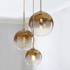 three glass globes hanging from a ceiling fixture in a room with white walls and flooring