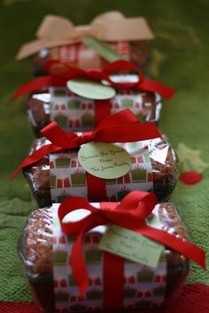 three wrapped gift boxes with red bows and tags on them sitting on a green surface