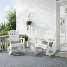 two white rocking chairs sitting on top of a wooden deck next to a potted plant