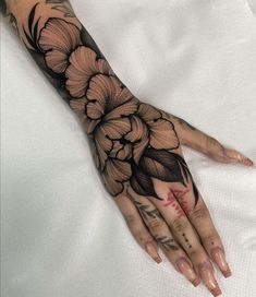 a woman's hand with black and white flowers on the left side of her arm