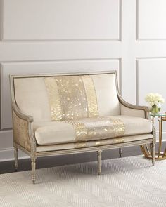 a white couch sitting on top of a rug next to a table with a vase