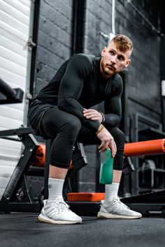 a man squatting on the ground holding a green object