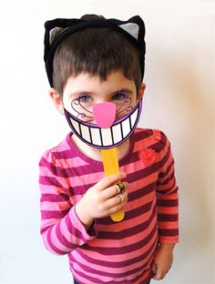 a young boy wearing a cat mask and holding a toothbrush