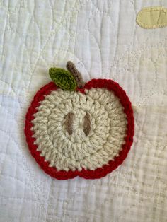 a crocheted apple on a white quilt