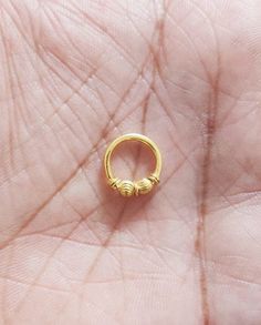 a small gold ring sitting on top of someone's hand