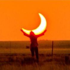 a person standing in a field with their arms outstretched and the sun setting behind them