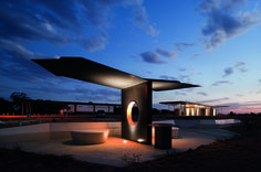 an artistic sculpture is lit up at night with the sky in the background and clouds above it