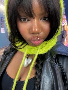 a woman with bright green hair wearing a black leather jacket and neon yellow ear rings