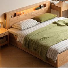 there is a bed with green sheets and pillows on the headboard, next to a night stand