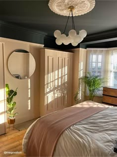 a bedroom with a bed, mirror and plant in the corner on the wall next to it