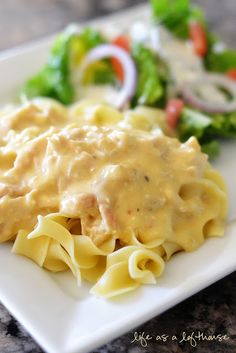 a white plate topped with pasta covered in gravy next to broccoli