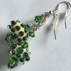 a pair of green and white beaded earrings sitting on top of a white surface