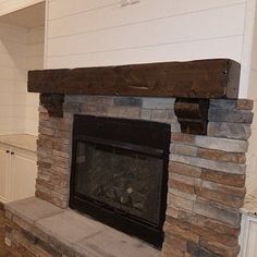 a stone fireplace in a kitchen with white cabinets