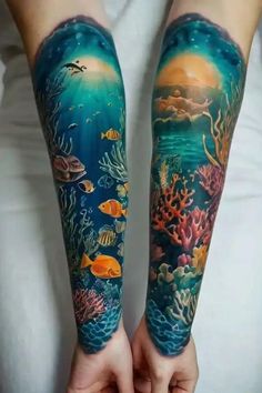 two people with tattoos on their arms holding hands in front of the ocean and fish