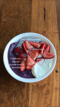 a bowl filled with yogurt and strawberries on top of a wooden table