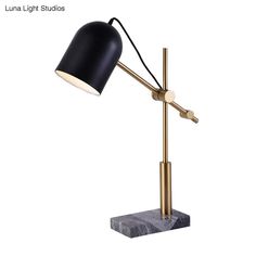 a black and gold desk lamp on a marble base with a white light behind it