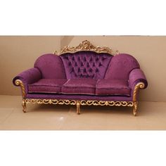 a purple couch sitting on top of a tile floor next to a white and gold wall