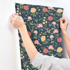 two hands are holding up a floral wallpaper