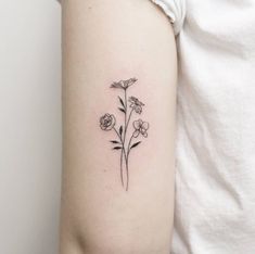 a small flower tattoo on the left side of the right arm, with three flowers growing out of it