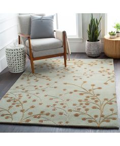 a living room area with a chair, potted plant and rug on the floor