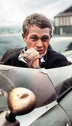 a man is sitting in an old car with his hand on his face and looking at the camera