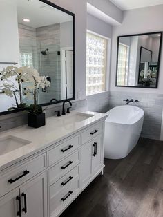 a large white bathtub sitting next to a sink in a bathroom under two mirrors