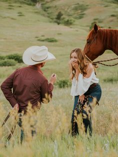 a woman standing next to a man in a field with a horse