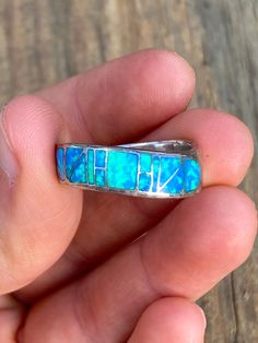 This striking size 9 ring is marked, '925' on the inside of the band and the band itself has a gentle wavy curvature to its overall shape. The front has a geometric pattern of blue fire opal inlay with stunning colors of firey blues and neon greens. I have not tested the Opal so there is a chance it is lab made but it looks genuine. It is being sold as is due to some surface wear to the metal band and it has the potential to polish up nicely. Blue Opal Inlay Ring For Anniversary, Blue Opal Ring With Inlay For Anniversary, Anniversary Blue Opal Ring With Inlay, Blue Inlay Rings For Anniversary, Blue Opal Open Ring In Sterling Silver, Blue Fire Opal, Blue Fire, Metal Band, Opal Ring